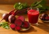 Sfecla roșie – cum să o consumi corect pentru a-ți susține sănătatea ficatului Felii de sfeclă roșie crudă și un pahar cu suc proaspăt, pe masă rustică, pentru consum sănătos și sprijinul ficatului.