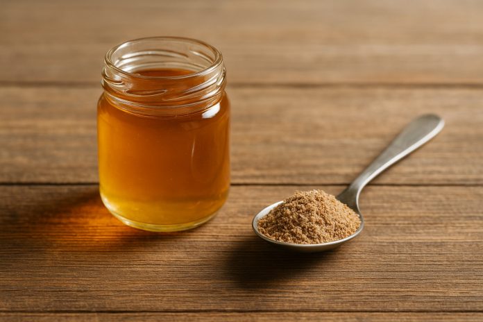 Borcan de miere și linguriță cu semințe de in măcinate pe masă rustică, simbol al unui remediu natural pentru sănătate.