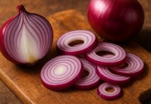 De ce e bine să consumi ceapă roșie. Ce arată studiile despre efectele ei asupra sănătății Ceapa roșie este unul dintre cele mai puternice alim Ceapă roșie tăiată pe un blat de lemn, imagine ilustrativă pentru beneficiile consumului de ceapă roșie