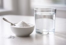 Cum te poate ajuta bicarbonatul de sodiu în calmarea simptomelor infecției urinare Bol cu bicarbonat de sodiu și pahar cu apă pe o masă luminoasă, utilizate ca remediu casnic pentru calmarea simptomelor infecției urinare.