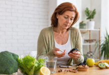 Femeie verificand glicemia cu glucometru si alimente sanatoase pe masa