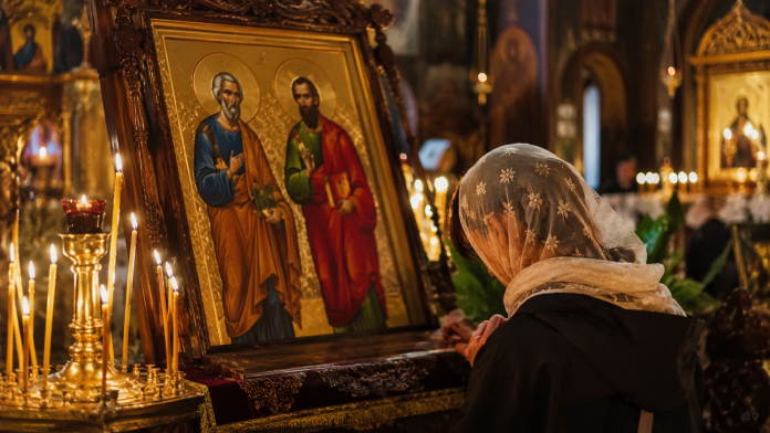 rugaciune-sfintii-petru-pavel.jpg Credincioasă rugându-se în fața icoanei Sfinților Apostoli Petru și Pavel cu o lumânare aprinsă