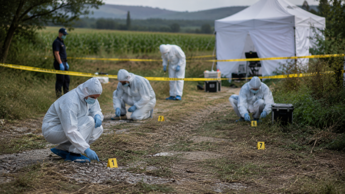 Criminaliști investigând un teren unde au fost descoperite rămășițe umane