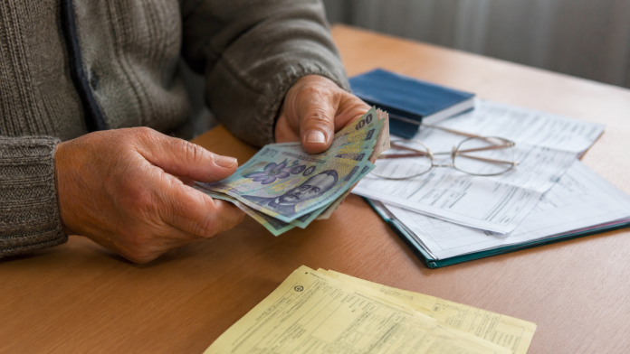 Pensionar numărând bani și documente privind ajutoarele financiare