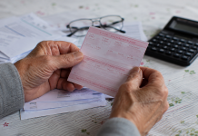 Guvernul acordă pensionarilor până la 1.000 de lei în două tranșe. Cine se încadrează Mâinile unui pensionar ținând un talon de pensie și documente financiare