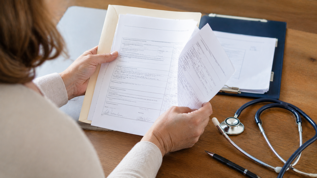 Persoană analizând documente medicale și acte necesare pentru obținerea pensiei de invaliditate.
