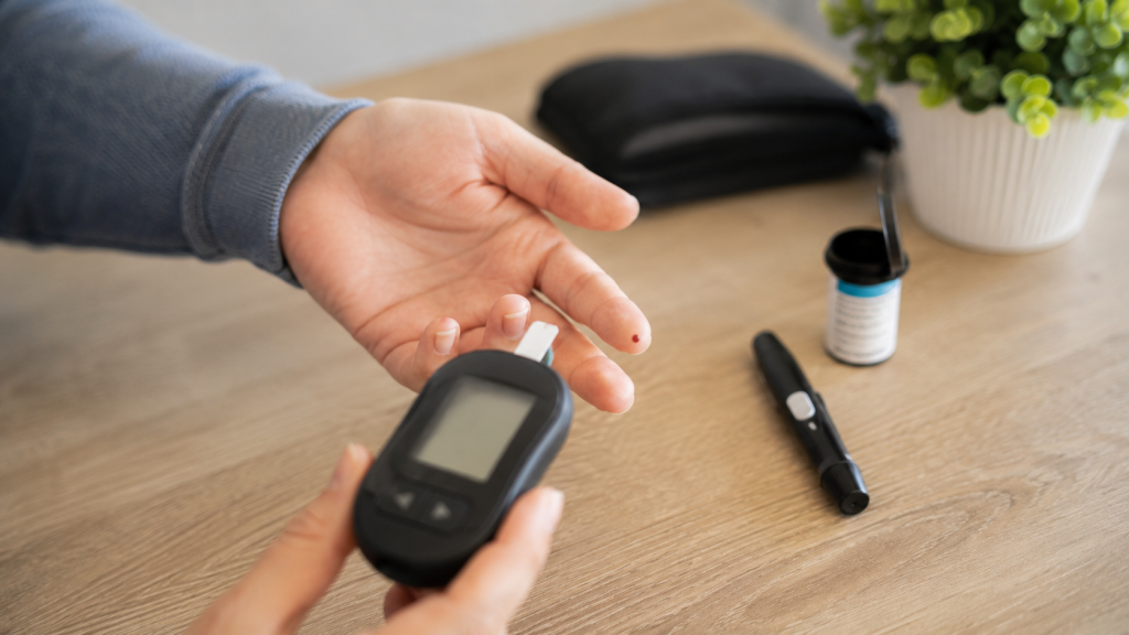Persoană ținând un glucometru lângă mâna pregătită pentru măsurarea glicemiei, simbolizând depistarea diabetului de tip 2.