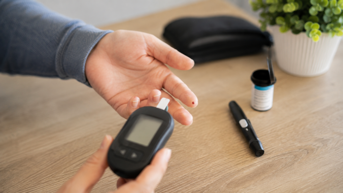 semne-diabet-tip-2.jpg Persoană ținând un glucometru lângă mâna pregătită pentru măsurarea glicemiei, simbolizând depistarea diabetului de tip 2.