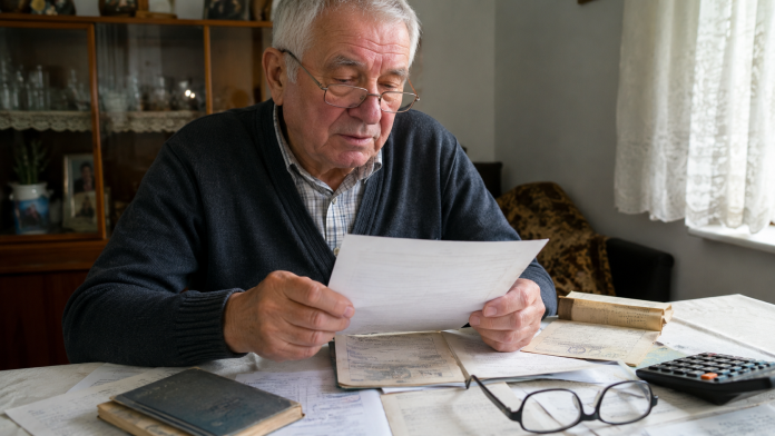 Pensionar care verifică documentele și adeverințele pentru veniturile obținute înainte de 2001 care pot conta la recalcularea pensiei.