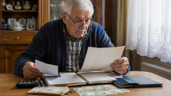 Pensionar verificând documente și adeverințe pentru recalcularea pensiei.