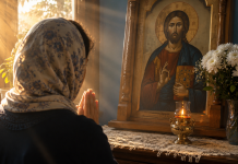 Femeie rugându-se în fața unei icoane ortodoxe, într-o dimineață de duminică, pentru sănătatea și ocrotirea familiei.