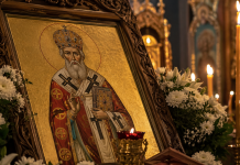 Icoană ortodoxă a Sfântului Alexandru, sărbătorit pe 30 august, într-o biserică luminată de lumânări.