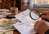Pensionarii care pot pierde bani fără să știe. Ce trebuie verificat pe talonul de pensie și când poți cere recalcularea Talon de pensie românesc verificat cu o lupă, alături de bancnote în lei și o decizie de pensionare, ilustrând verificarea drepturilor și recalcularea pensiei.