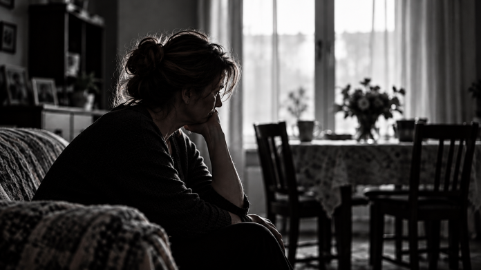 femeia-care-a-uitat-de-ea.jpg Femeie matură stând singură la masa din bucătărie, într-un moment de tristețe și reflecție, după ani în care s-a ocupat de familie.